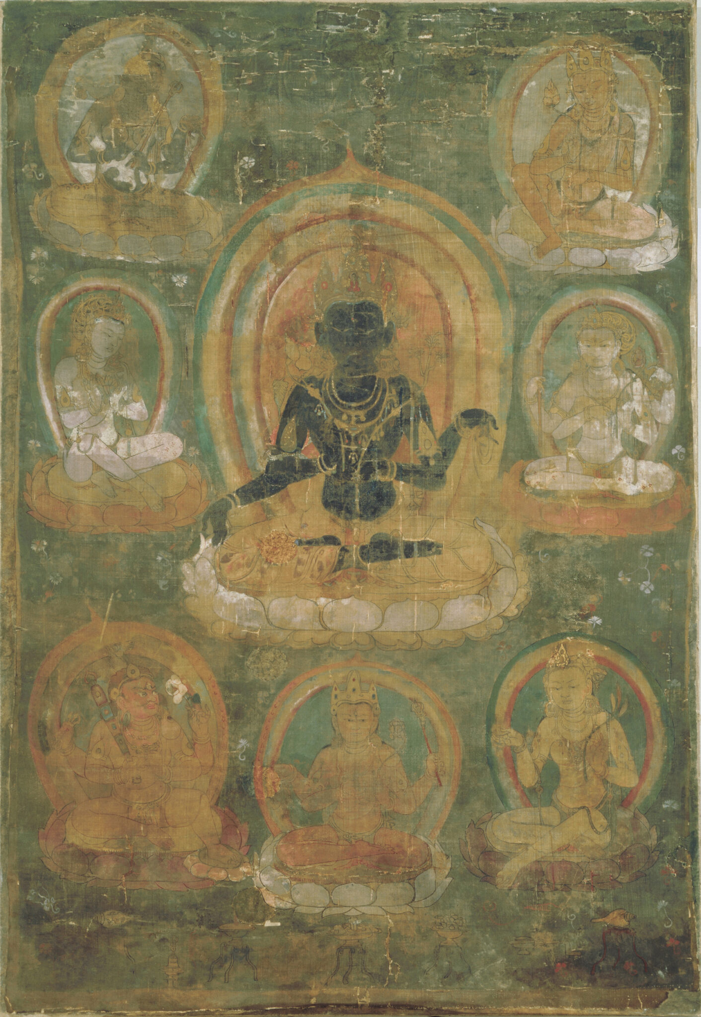 Deity with dark skin seated on lotus pedestal surrounded by seven smaller deities against green background