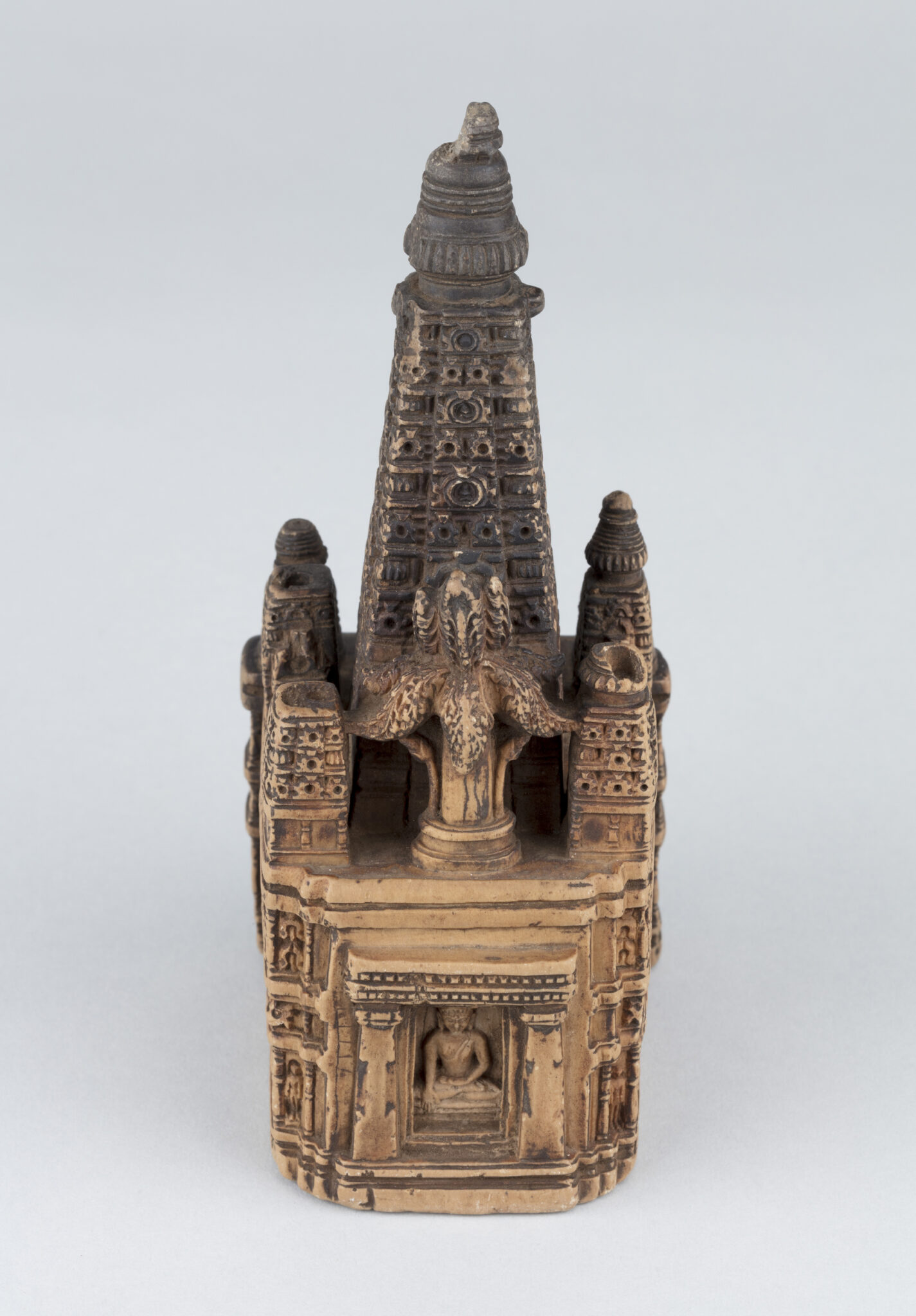 Side view of miniature architectural model with register of seated Buddhas at base and slender tapered roof