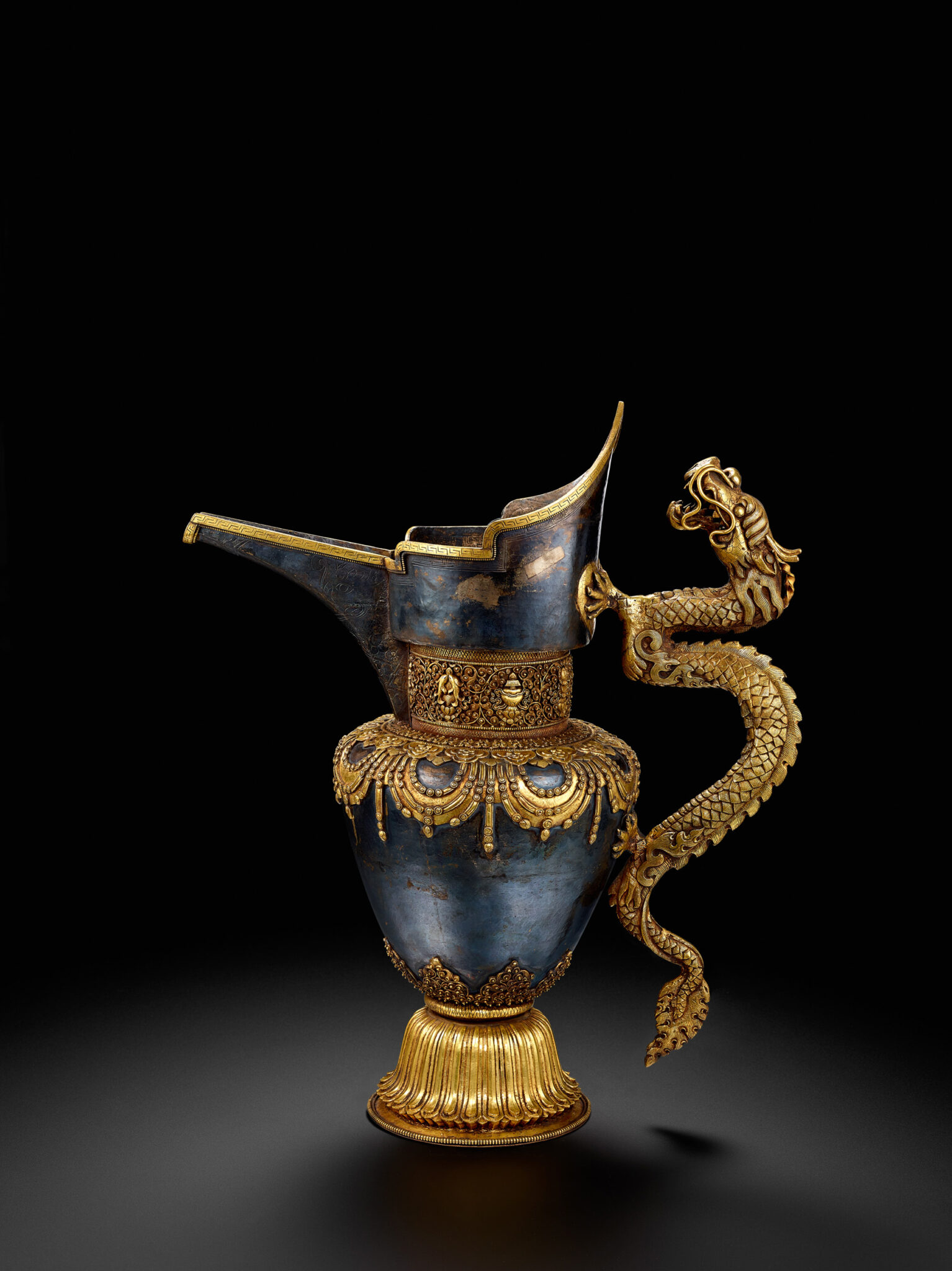 Silver pitcher with crown-shaped rim and golden decoration at base and neck; features dragon handle