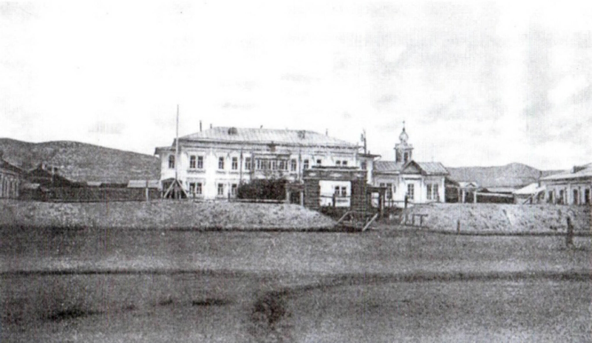 Black and white photograph of two-story building in Russian style; Onion dome atop structure at right