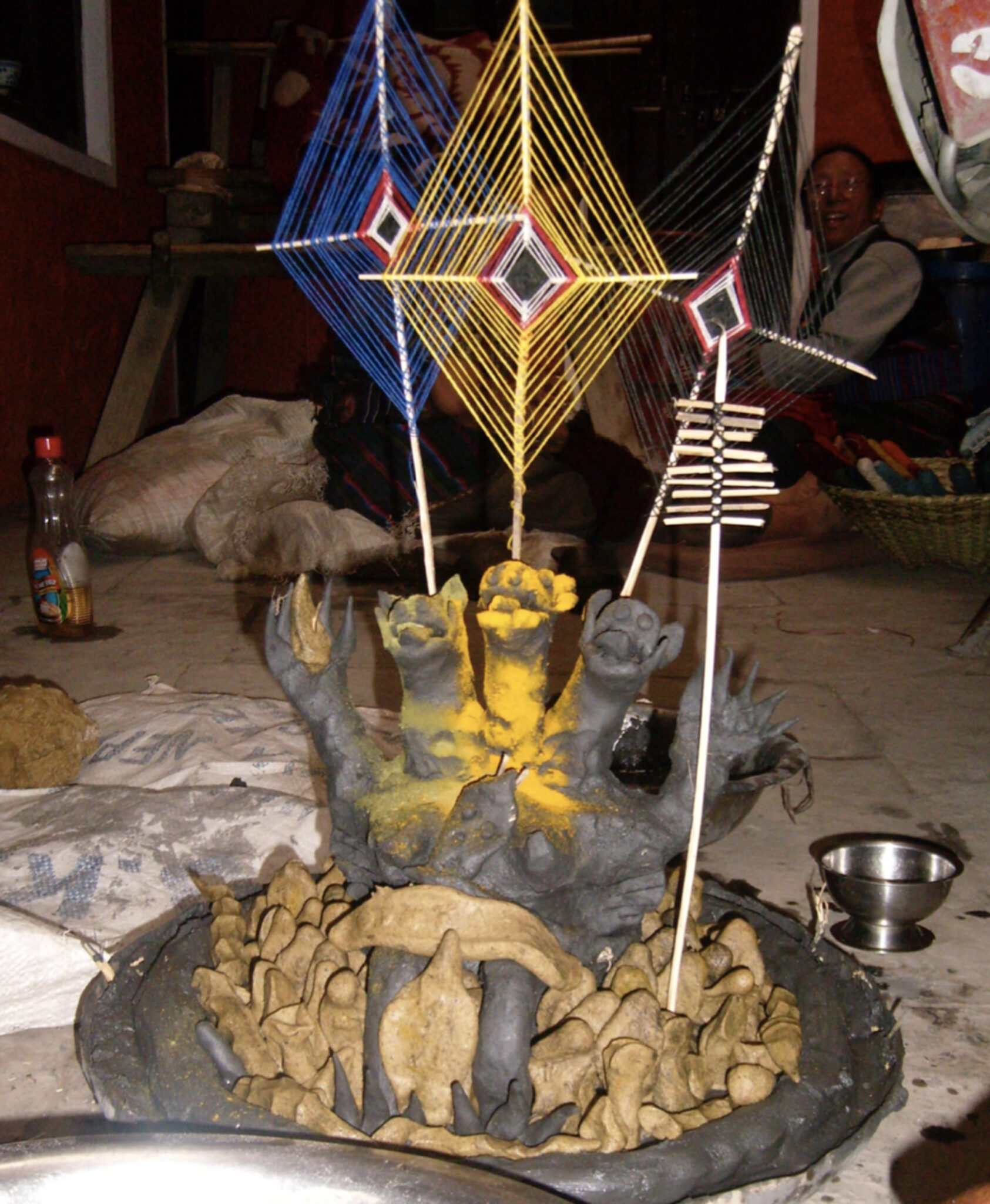 Effigy of three-headed figure daubed with yellow pigment supporting three yarn-woven lozenges on sticks