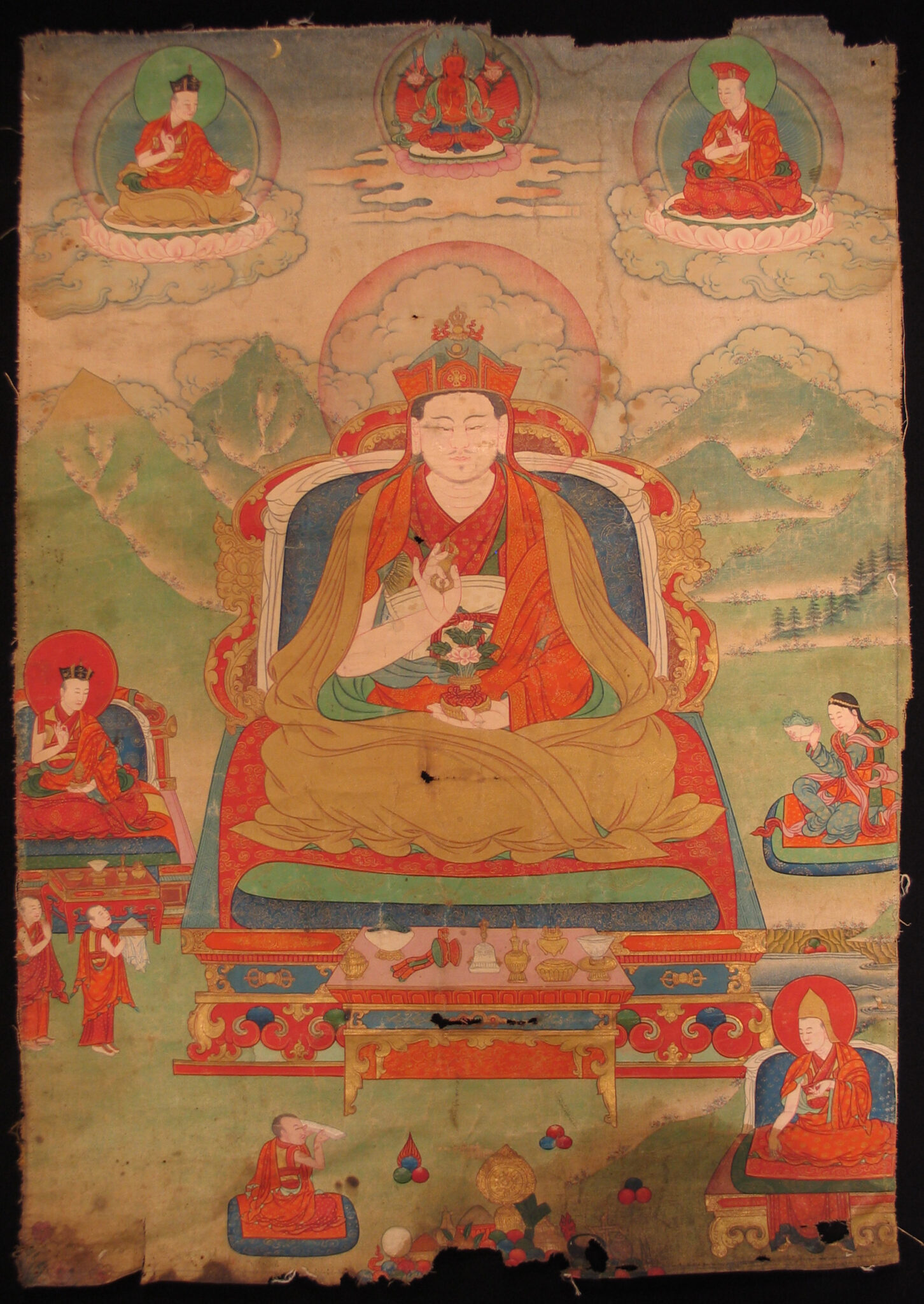 Lama seated on throne with vajra in left hand, suspended above mountainous landscape, surrounded by portraits