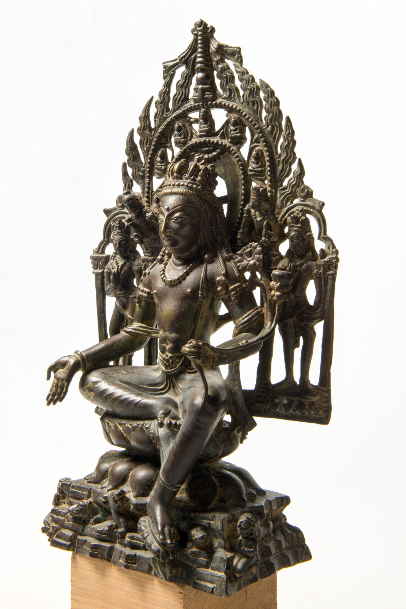 Statue of Bodhisattva seated before mandorla; viewed in medium three-quarter profile