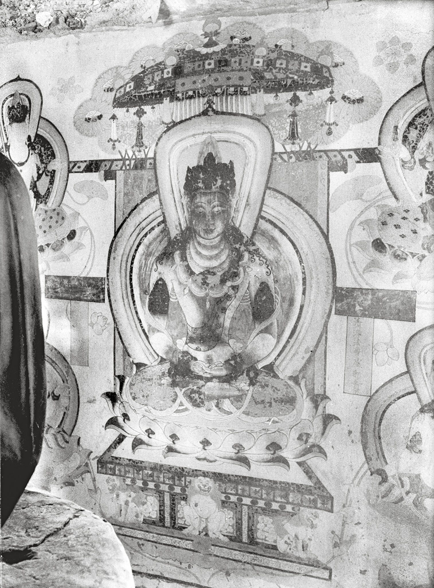 Black and white image of wall painting depicting haloed deity seated on lotus pedestal