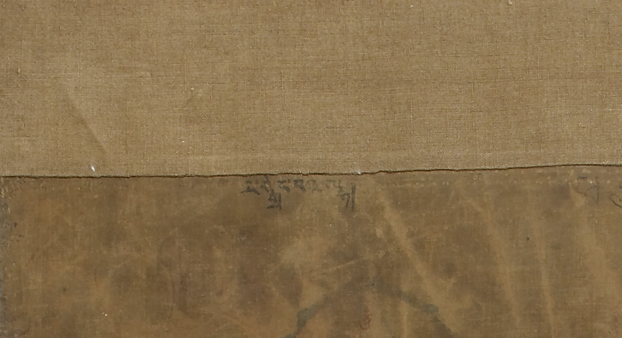 Close view of beige, textured surface with short line of Tibetan script at center underneath horizontal seam