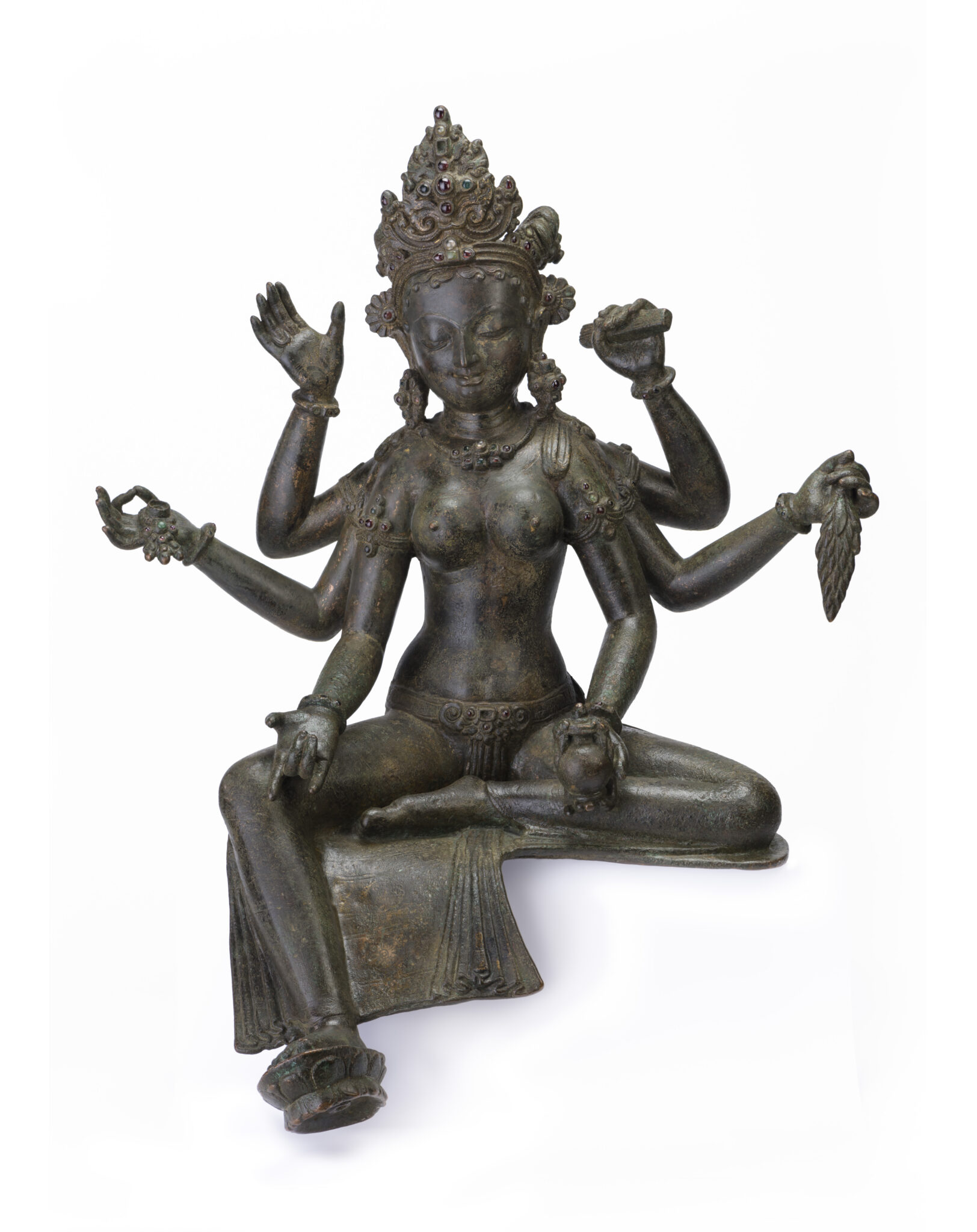 Patinated dark metal statue of six-armed goddess seated with left foot resting on lotus blossom