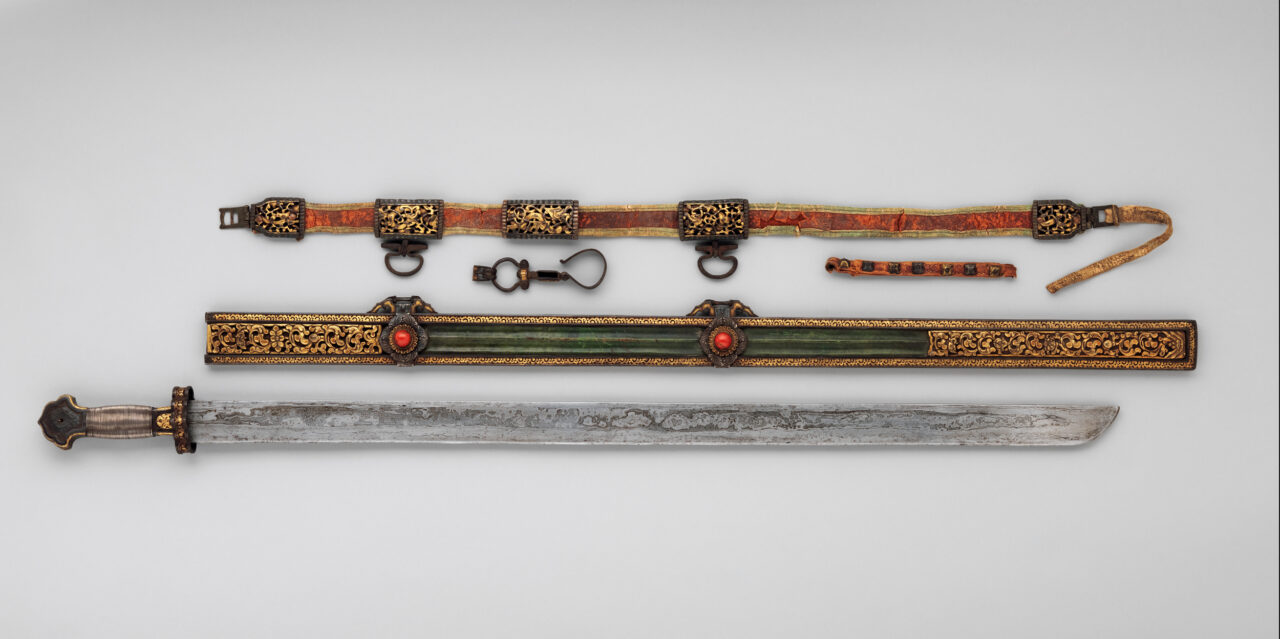 From bottom: sword with tarnished blade; scabbard inset with two red stones and scrolling foliage; orange belt with filigreed mounts and buckles