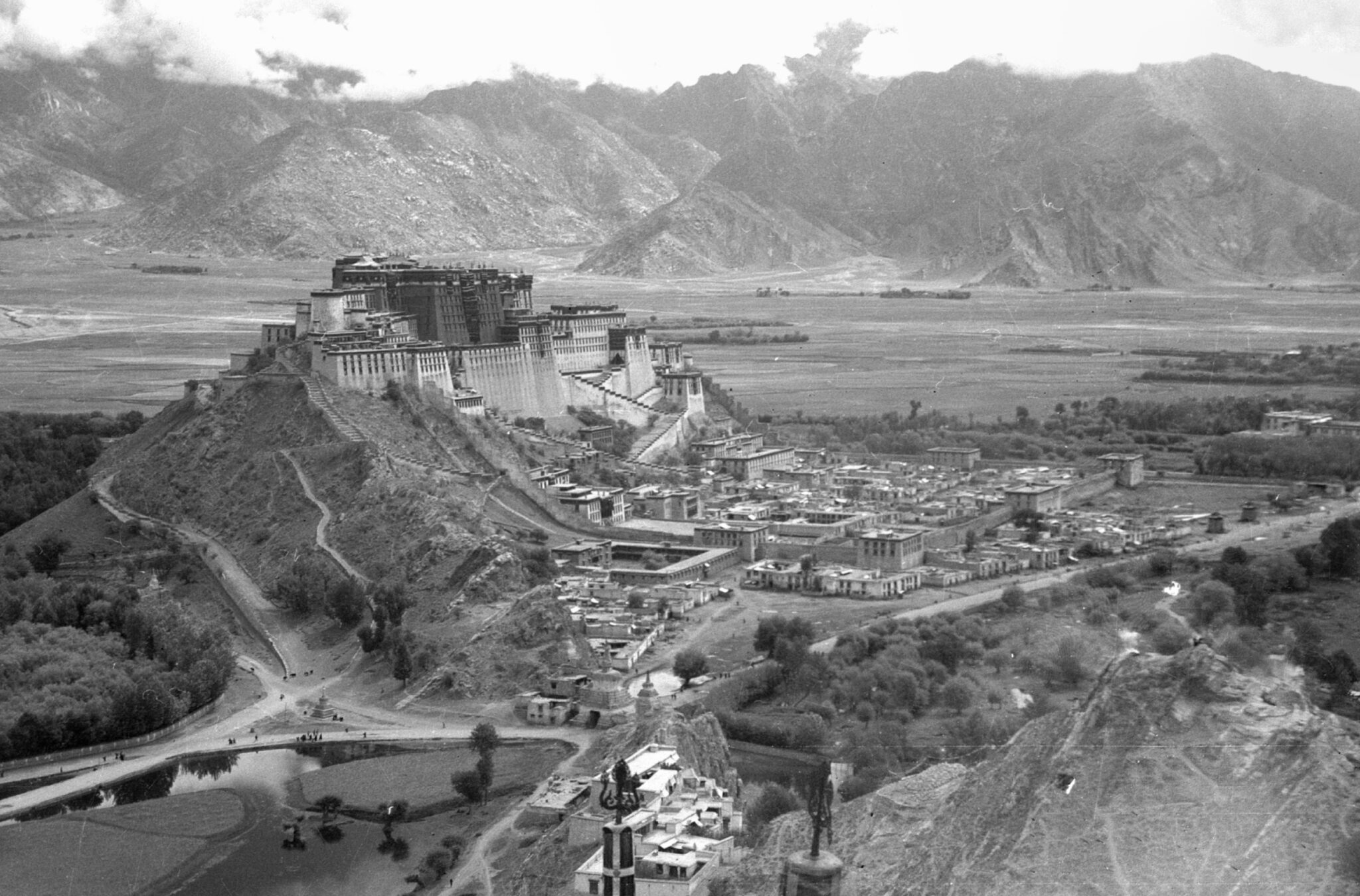Black and white aerial photograph of palace complex situated on peak of hill within mountain valley
