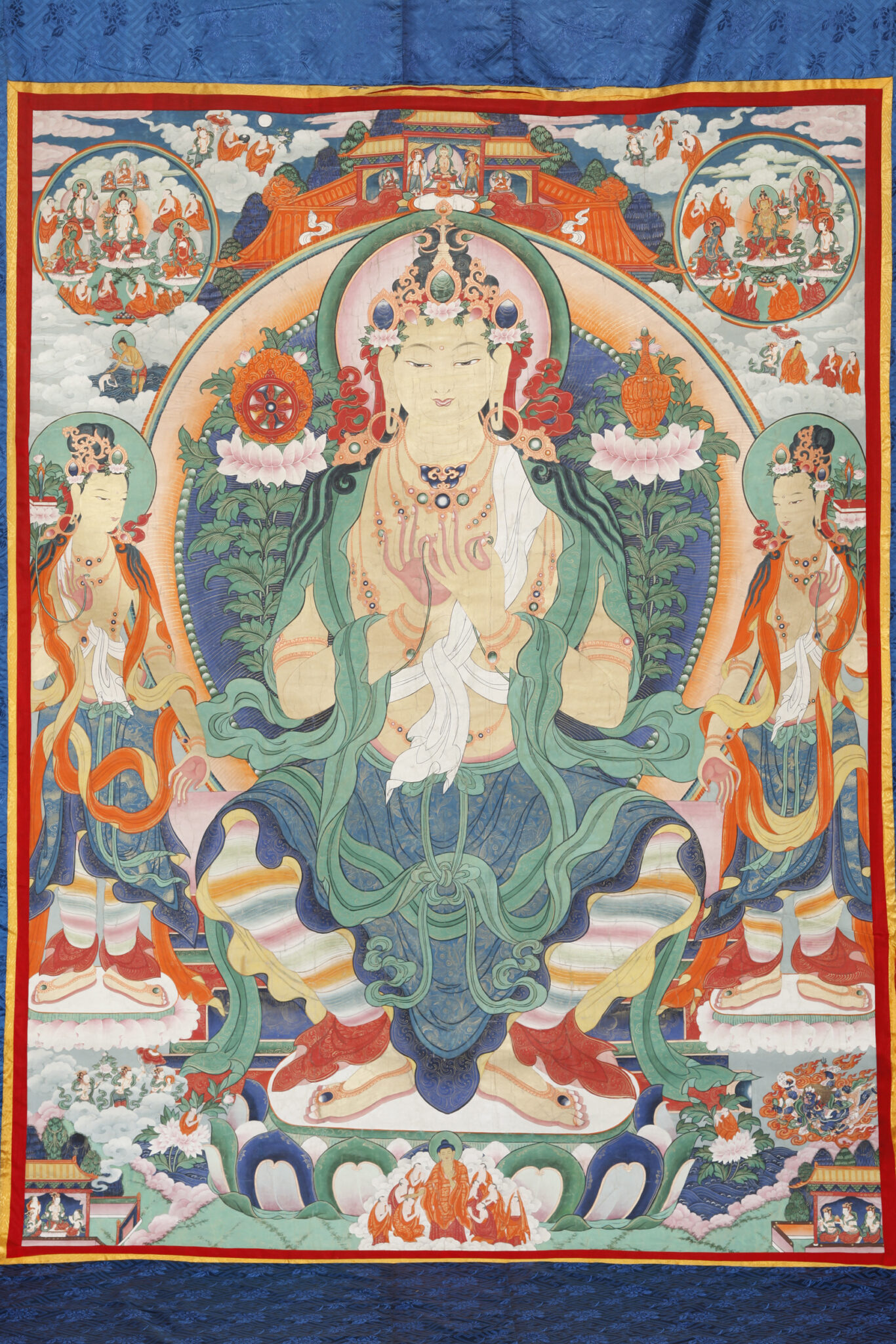 Painting mounted on blue damask depicting Buddha wearing resplendent green and blue garment