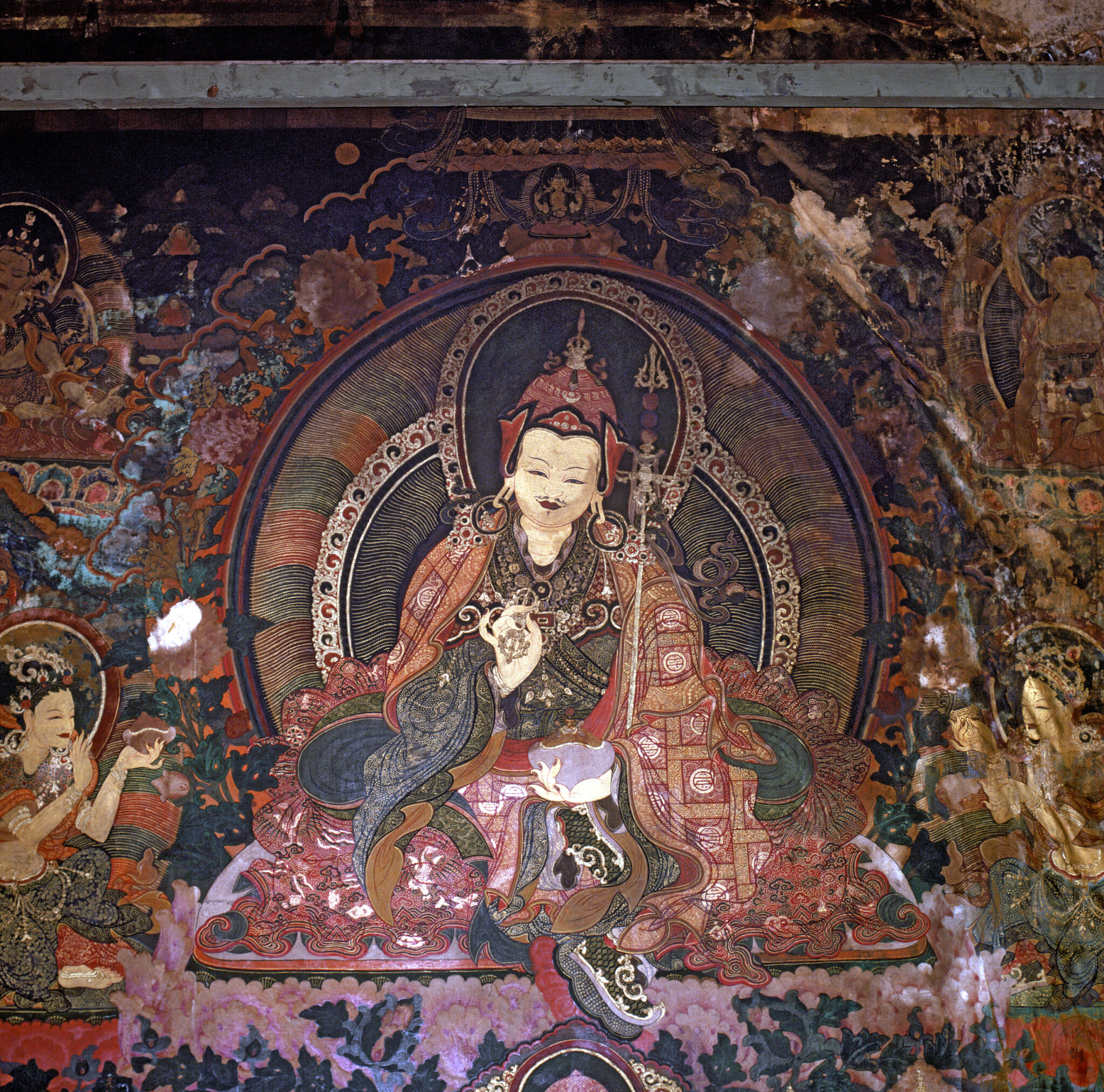 Guru wearing patchwork robe with staff at right shoulder, bowl in right hand, and vajra in left