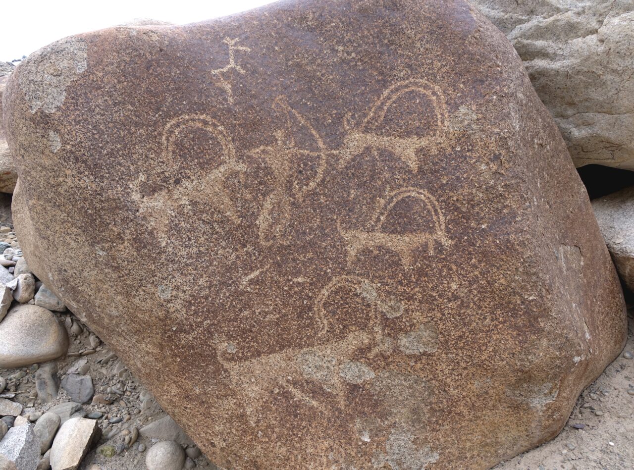Depiction of archer hunting horned animals on orange-brown boulder