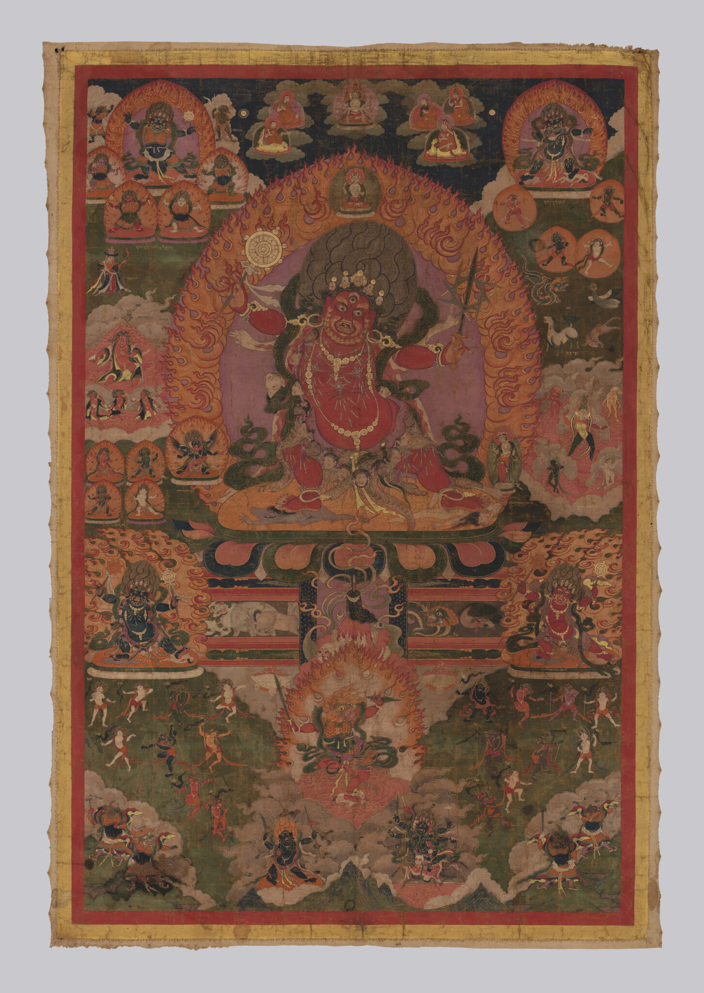 Wrathful deity stands in dynamic pose before fiery nimbus, surrounded by deity portraits