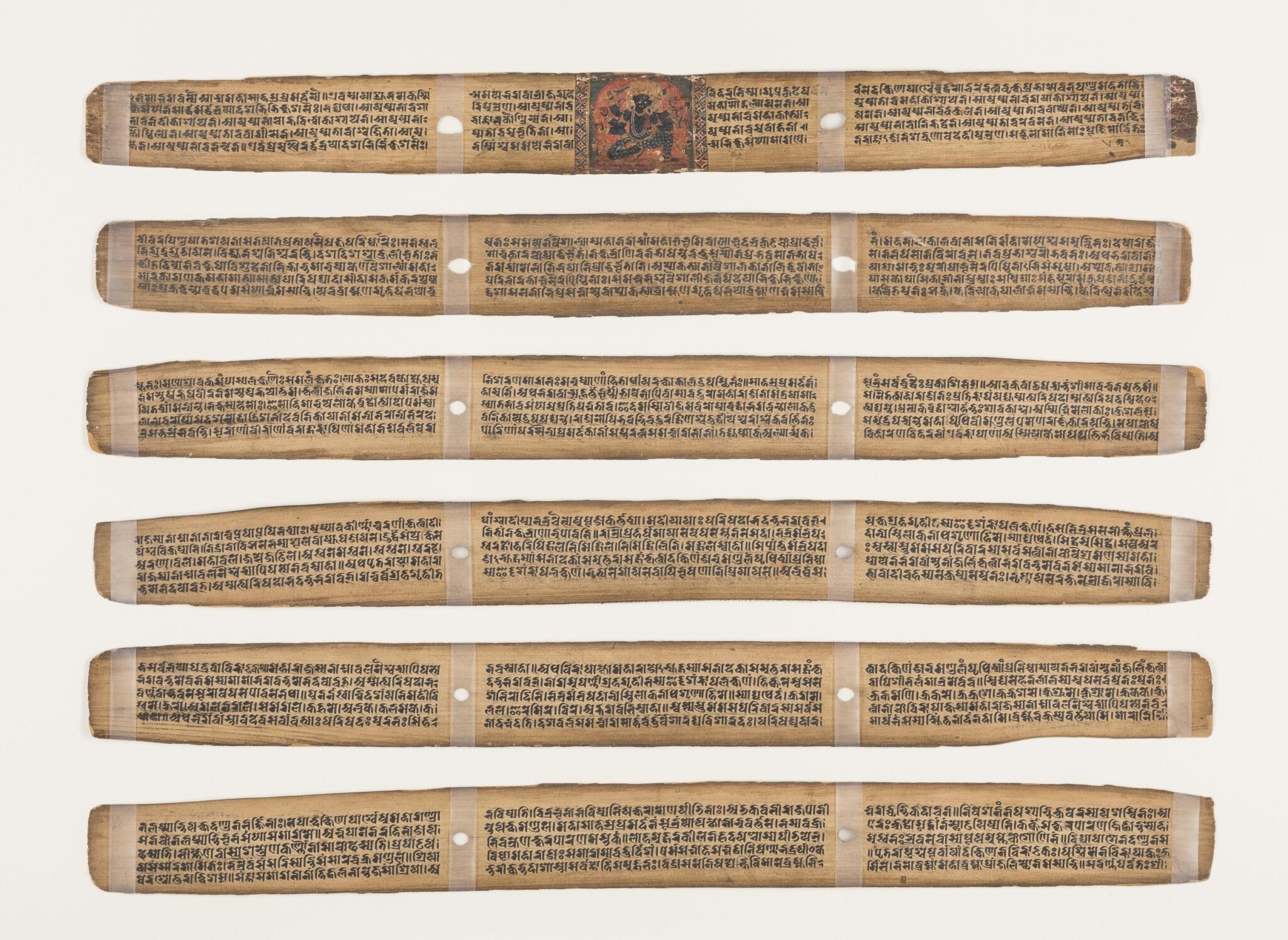 Six long rectangular pages bearing script and two puncture holes each; top page features deity portrait in center