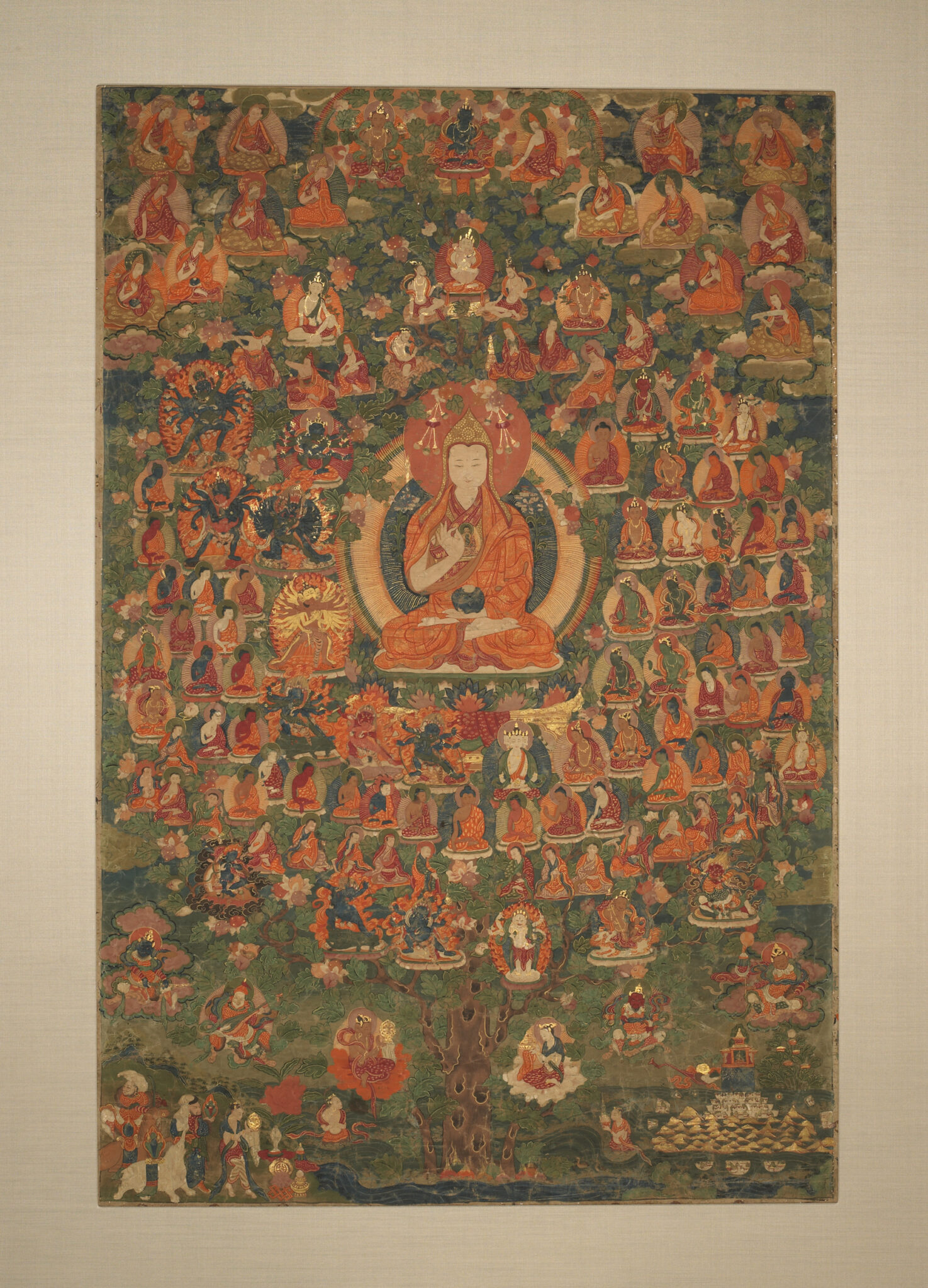 Monk seated in tree, surrounded by dozens of portraits, which hang like leaves from the branches