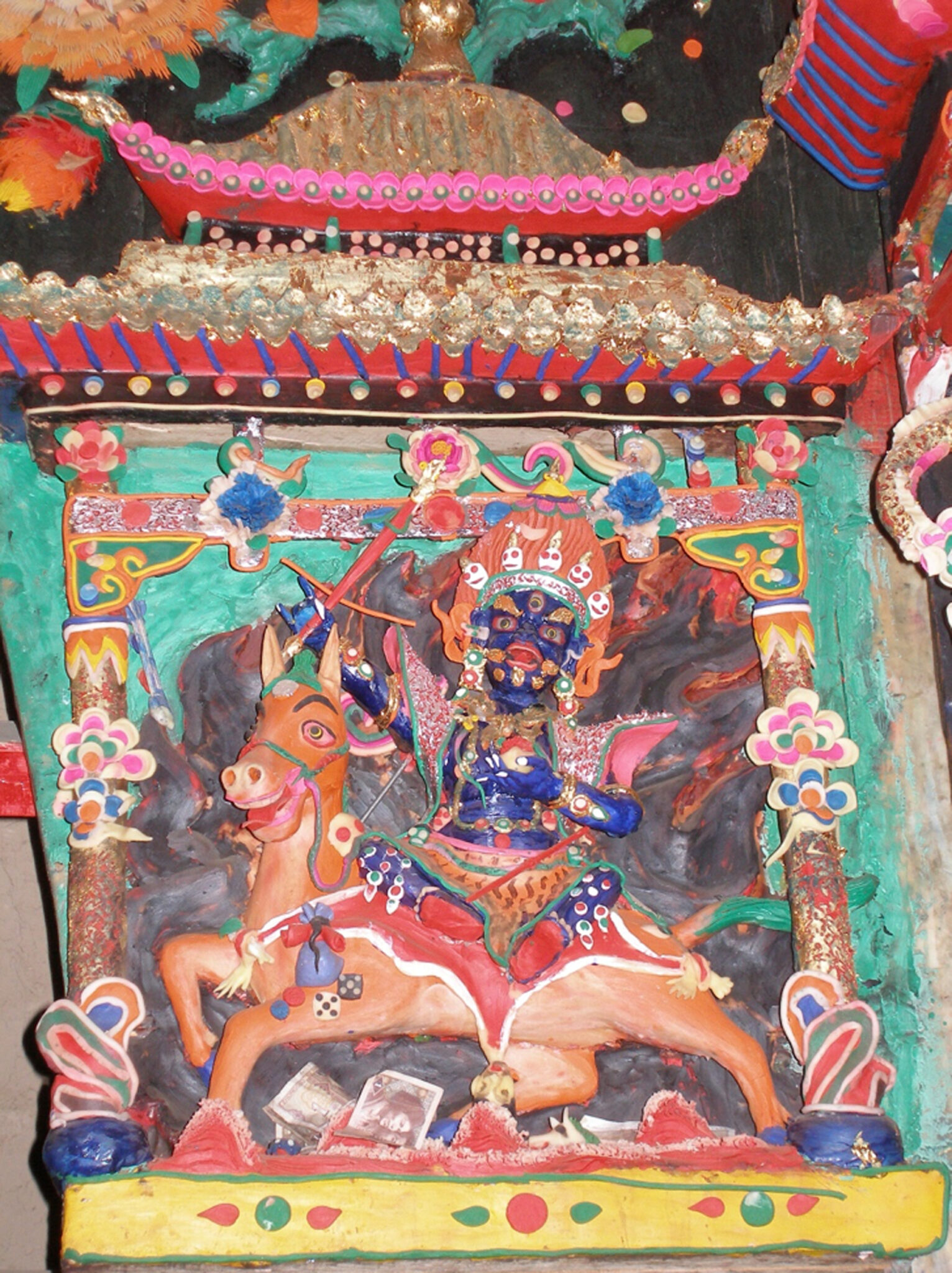 Colorful butter sculpture depicting wrathful deity with blue skin and crown of skulls riding atop horse