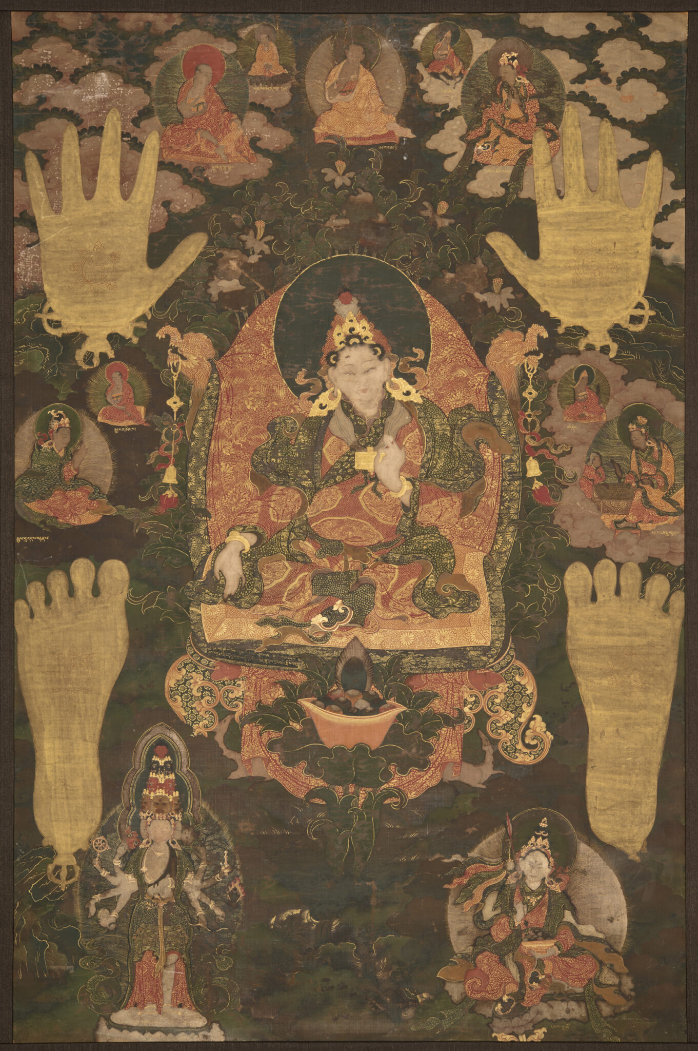 Pair of hand- and footprints frame holy man seated against background featuring deity portraits and vegetation